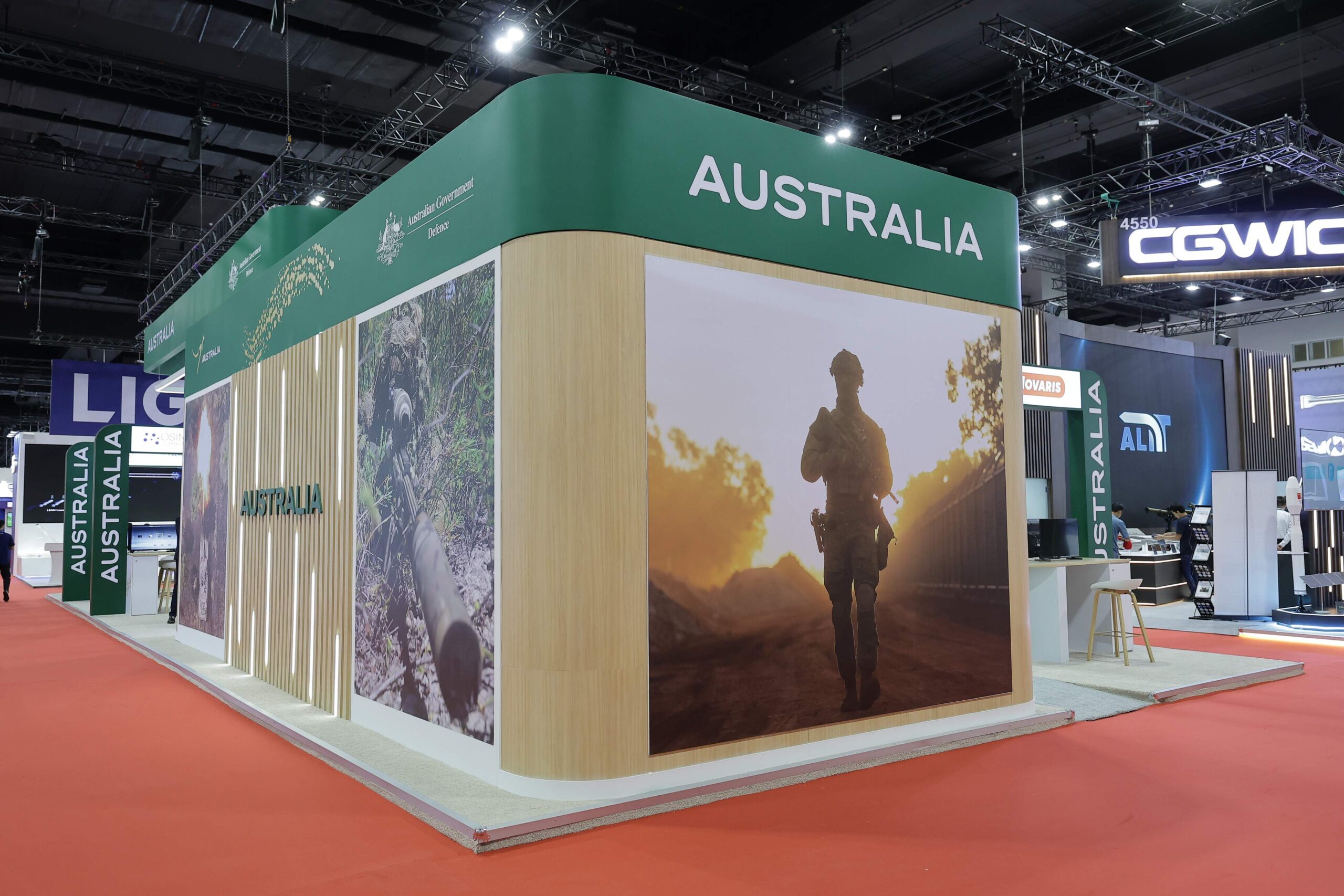 Exhibition booth with 'AUSTRALIA' banner in green, wood-paneled walls and large photo panels at a trade show.