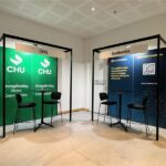 Two exhibit booths with black frames: left CHU green banners and chairs, right Guidewire blue panels with stools and signage.