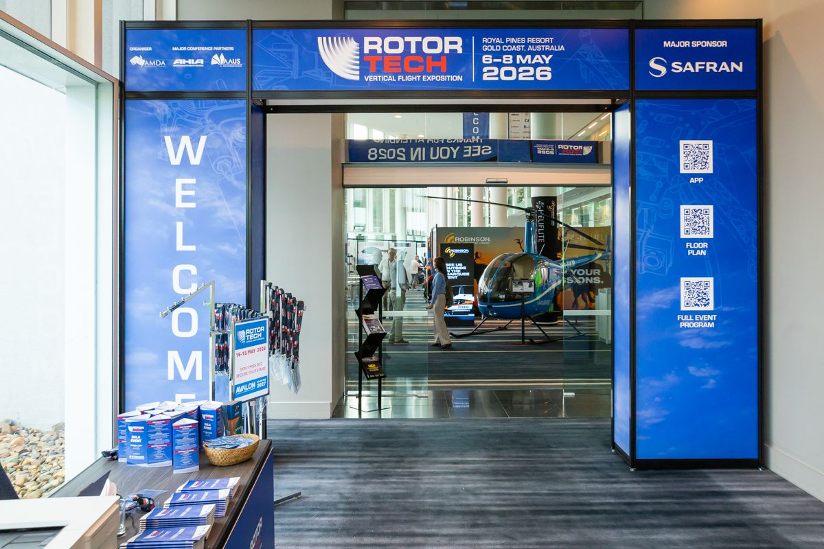 Entrance to Rotor Tech vertical flight expo with blue welcome panels and a small helicopter display inside.