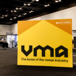 Large yellow VMF display panel at a convention hall featuring the slogan 'The home of the venue industry' and Moretonhire as sponsor.