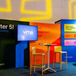 Trade show booth featuring After 5! Networking on a black panel, a VMA screen, and tall tables with stools.