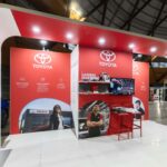 Toyota exhibition booth with red panels and large Toyota logos at an indoor trade show.