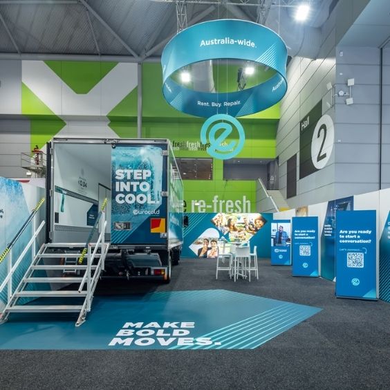 Exhibition booth with a blue Eurocold truck, stairs, and a large 'STEP INTO COOL' graphic under a circular hanging sign reading 'Australia-wide.' plus a bold 'MAKE BOLD MOVES' floor graphic.